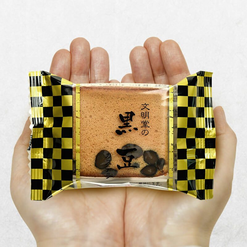 手のひらに乗った文明堂の黒豆カステラ 1個 （商品番号：K137）